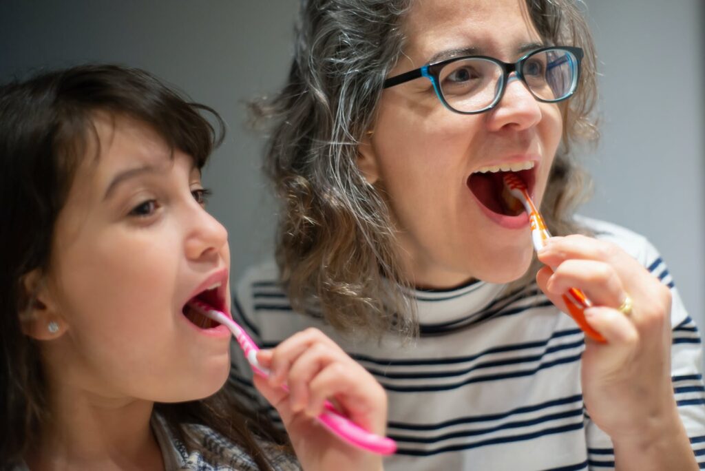 Mujer y Niño Cepillándose los Dientes Juntos